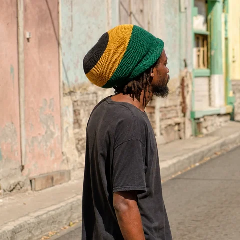 Man in a green, gold and black tam on a Kingston street